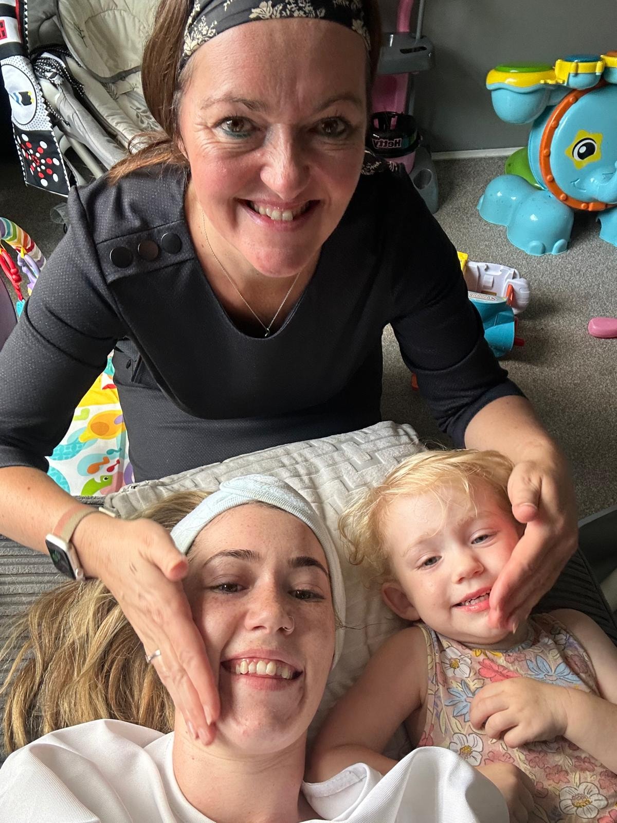 Mandie giving a gentle wellbeing treatment to a mum while her baby rests beside them